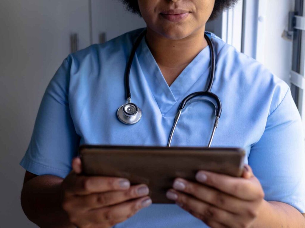 African american mid adult female nurse with afro hair using digital tablet in hospital